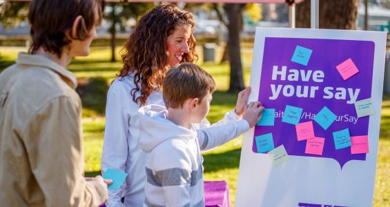 Three people placing post-its on Have your Say board