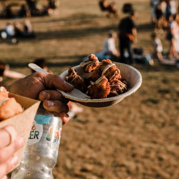 Person holding bowl of fried chicken pieces at Street Eats