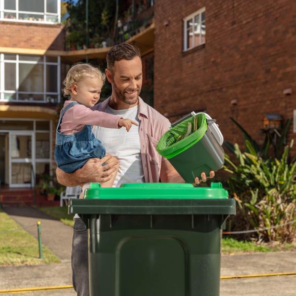 Man and daughter placing food organics in green bin