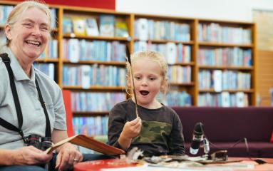 Child holding up a feather at a library