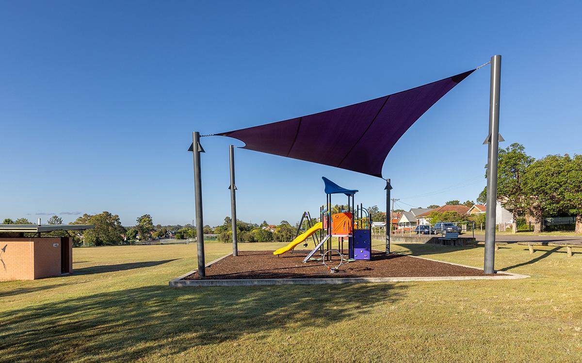 Side view of playground under sun shade and amenities